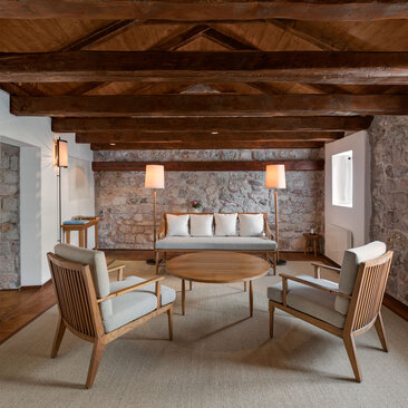 Grand Cottage seating area at Aman Sveti Stefan, with wooden beamed ceiling and stone walls.