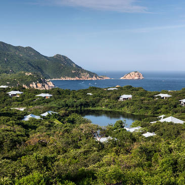 Lake Pavilion at Amanoi overlooking coastal Vietnamese landscape with forested hills and blue waters.