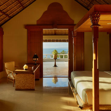 Ocean Suite principal bedroom at Amankila resort, Bali, with terracotta archway framing plunge pool and sea view.