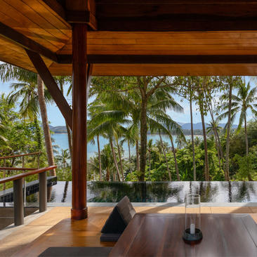安缦璞瑞度假村的海滨泳池馆，木质结构框架俯瞰棕榈林景观和大海。