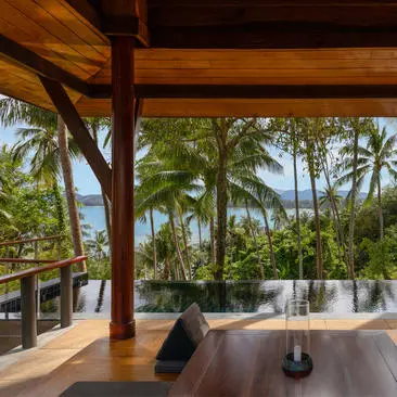 Partial Ocean Pool Pavilion at Amanpuri with wooden beams framing views of palm trees and Andaman Sea, Thailand.