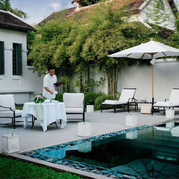 Pool suite at Amantaka with stone terrace, loungers, and verdant garden backdrop.