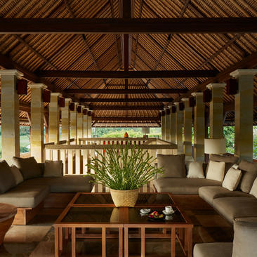 Three-bedroom villa lounge with timber ceiling, stone columns and garden views at Aman Villas at Nusa Dua.