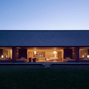 Tsuki Villa at Amanemu glows warmly as dusk falls, its modern architecture framed against a twilight sky.