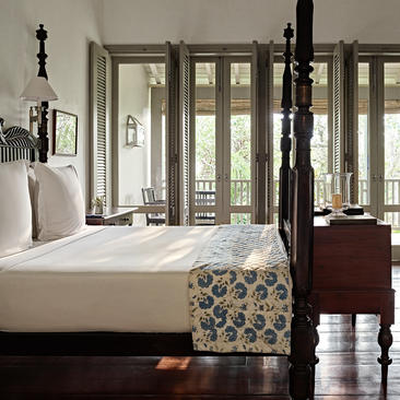 Principal bedroom at Amangalla with verandah doors opening to natural light, wooden flooring and period furnishings.