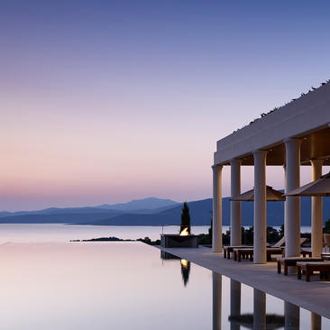 Villa overlooking calm waters at dusk, Amanzoe resort, Greece.