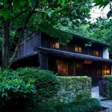 法云安缦度假村中，一栋现代建筑在夜幕降临时亮起灯光，被郁郁葱葱的绿色植物和树木环绕。