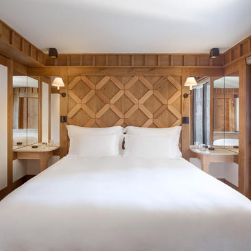 Junior bedroom at Aman Le Mélézin with geometric wood headboard and built-in bedside tables.