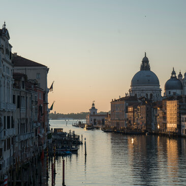Venice's Grand Canal at dawn, with the Basilica di Santa Maria della Salute reflected in still waters.