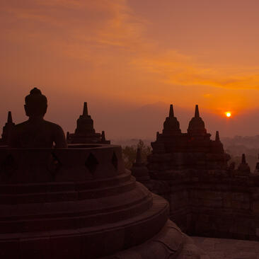 Silhouetted temple spires at Amanjiwo rise against a golden sunrise in Indonesia.