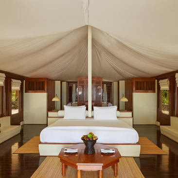 Amanwana villa bedroom with draped canvas ceiling, four-poster bed and wooden furnishings.