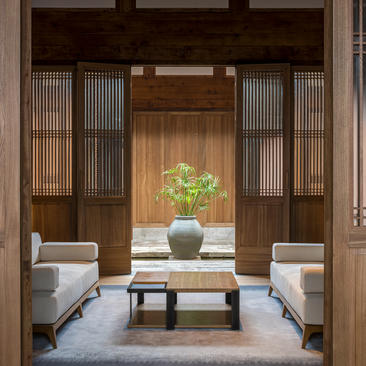 Amanyangyun gallery pavilion with wooden doors, central table and ceramic vessel, flanked by seating areas.