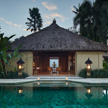 Amandari suite with thatched roof pavilion reflected in still pool at dusk, Bali.