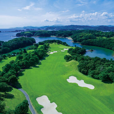 安缦伊沐高尔夫球场的航拍图，绿色球道穿过林地，蓝色水域点缀其间。