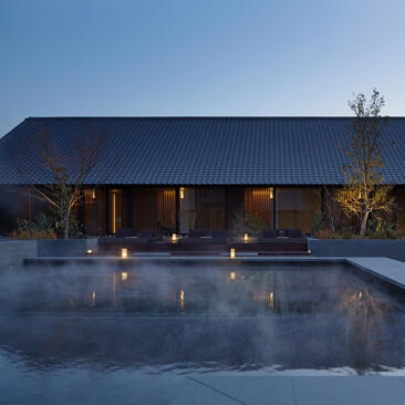 アマネムのリゾートの屋外温浴施設、夜間照明に映える建築と静寂の水面。