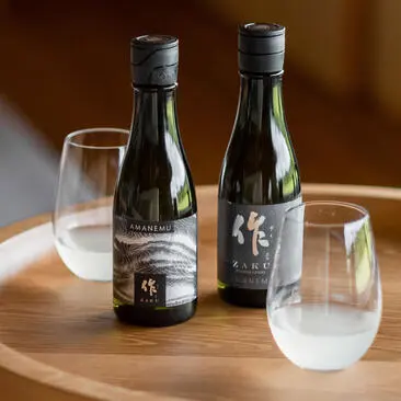 Two wine bottles and glasses on a wooden table at Amanemu dining venue.