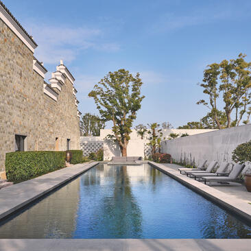Reflective pool flanked by stone walls and verdant landscaping at Amanyangyun, China.