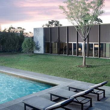 Swimming pool with loungers at Amanyangyun residence, China, at dusk with modern architecture beyond.
