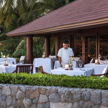 Clubhouse dining pavilion at Amanpulo with al fresco table settings and server in the Philippines.