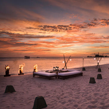 Wooden boats moored on sand at sunset, Amanpulo.