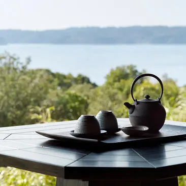 Tea service with black teapot and cups overlooking coastal waters at Amanemu.