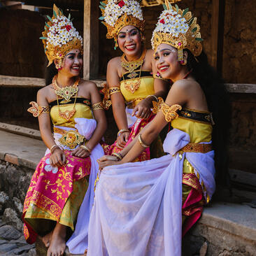 Three women in traditional Balinese dress with ornate golden headdresses at Amankila.