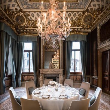 Salle à manger élégante avec lustre en cristal et plafond orné à l'Aman Venice.