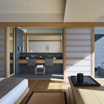 Aman Tokyo suite bathroom with dual vanity, dark cabinetry, and natural light from large windows.
