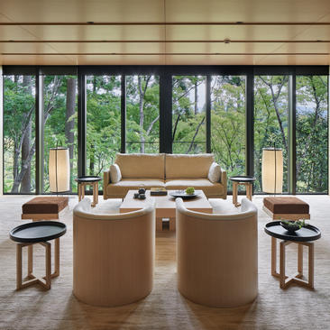 Washigamine Suite at Aman Kyoto with curved seating, expansive windows overlooking gardens, and natural wood furnishings.