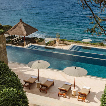 Main pool at Amankila overlooking the ocean, with sunloungers and parasols.
