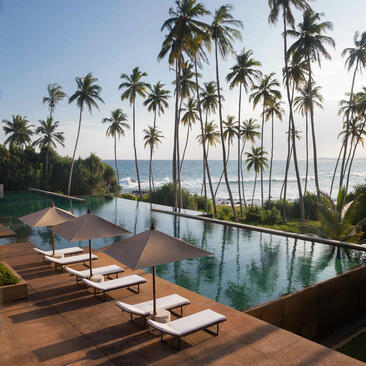 Poolside loungers overlook an infinity pool and Indian Ocean at Amanwella, Sri Lanka.