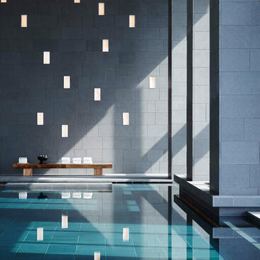 Piscina interna con pareti grigie e luci sospese, Aman Tokyo.