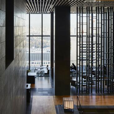 Corredor con paredes grigio scuro, divisorio in legno e vista sulla città presso Aman Tokyo.