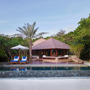 Beach Pool Casita at Amanpulo with burgundy roof, viewing platform, and palm trees beside still water.
