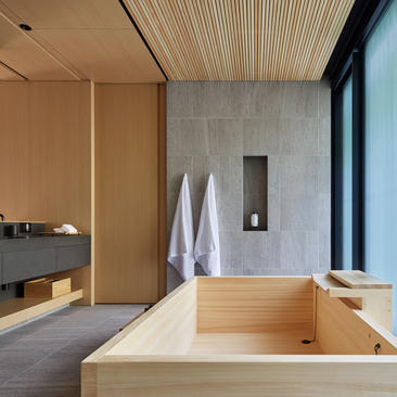 アマン京都のリゾートにある、木製の浴槽と木製天井、モダンな洗面エリアを備えた浴室。