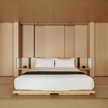 アマン京都のリゾートに佇む、木製フレームと白いファブリックで構成された現代的なベッド。