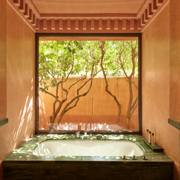 Pavilion interior at Amanjena resort with framed garden view through open window and cushioned seat.