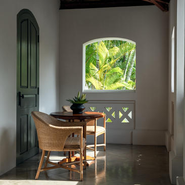 Pool Suite sitting area at Amantaka, with wooden desk, green mirror, and garden views through arched window.