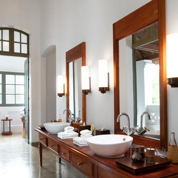 Amantaka Pool Suite bathroom with dual vanity, wooden-framed mirrors, and white walls.