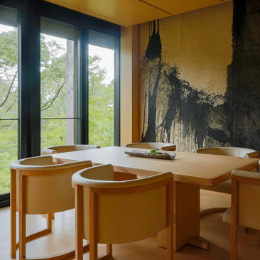 アマン京都の高峯スイートのダイニングテーブル。木製の家具と大きな窓から庭園を望む。