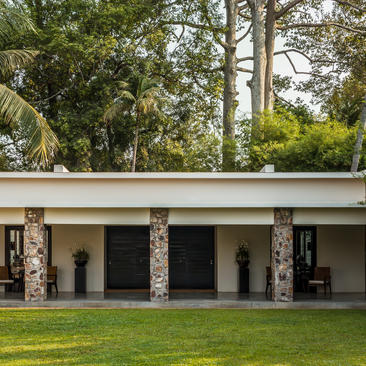 Amansara pavilion with stone columns and open-air design, surrounded by tropical gardens.