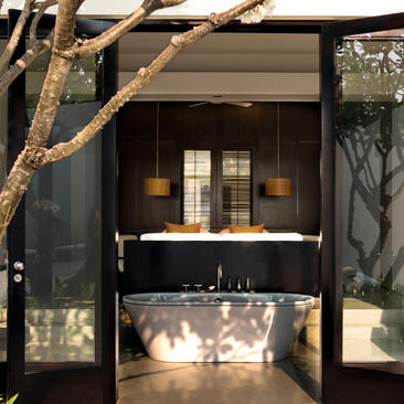 Amansara room entrance with dark wooden doors, illuminated interior, and natural branch detailing.
