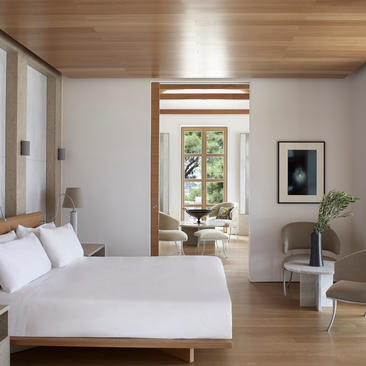 安缦卓熠度假村的宽敞主卧室，配有木质天花板、落地窗和极简装饰。