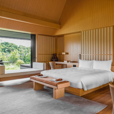 Suite bedroom at Amanemu resort with wooden interior, large window and garden views.