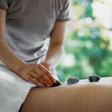 Hot stone massage treatment at Amanemu with therapist placing heated stones on guest's back.