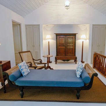 A serene bedroom at Amangalla with a blue bed, wooden furniture, and soft lighting.