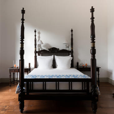 Principal bedroom at Amangalla with four-poster bed and misty landscape view.