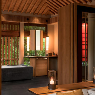 Amanoi pavilion bathroom with wooden ceiling, soaking tub, and view to garden.