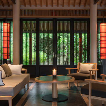 Pavilion sitting area at Amanoi with lounge seating facing green-shuttered front doors and round wooden table.