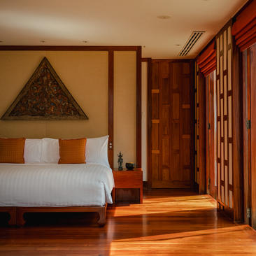 安缦璞瑞度假村的卧室，木制框架床铺配白色床上用品，木质地板和传统装饰。